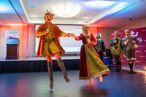 Para tancerzy w strojach i maskach historycznych unosi się w powietrzu podczas występu na gali Turystyczne Skarby Małopolski